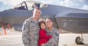Alex Sawin in her Air Force uniform standing beside her husband and holding her young daughter