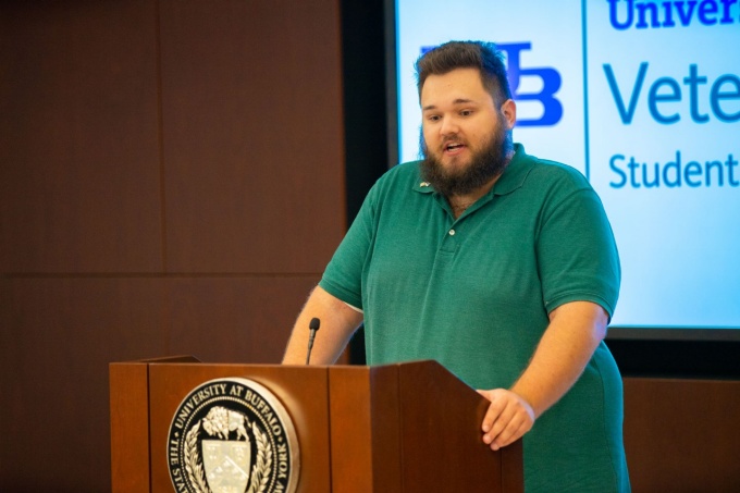 A student veteran speaking into a microphone while standing at a podium