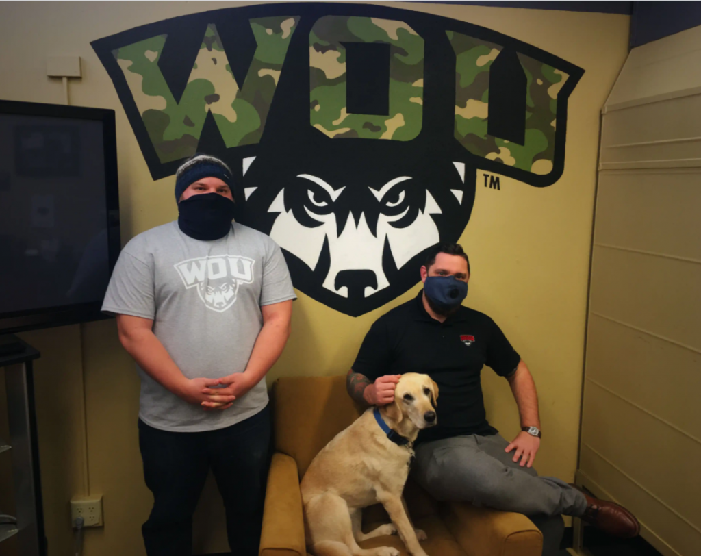 Two student veterans posing with a dog