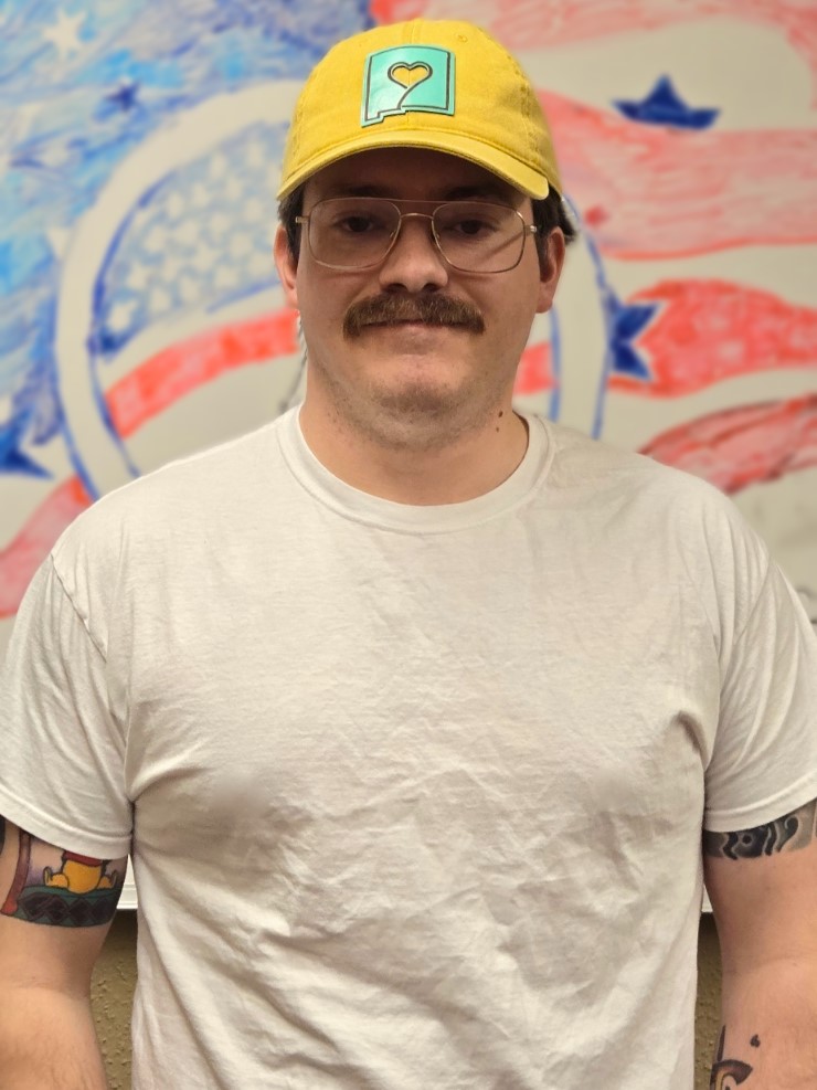 Smiling man with a mustache standing in a yellow hat