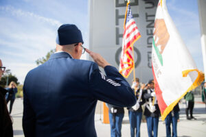 Person in military uniform saluting the national and state flag