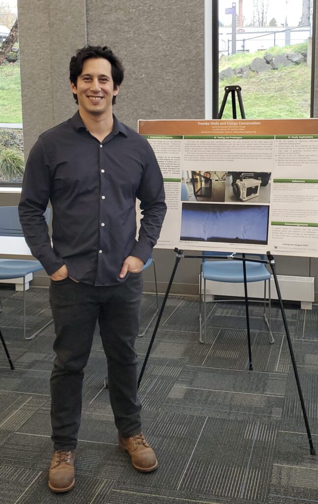 Figure with hands in pockets standing in front of a poster presentation and smiling.