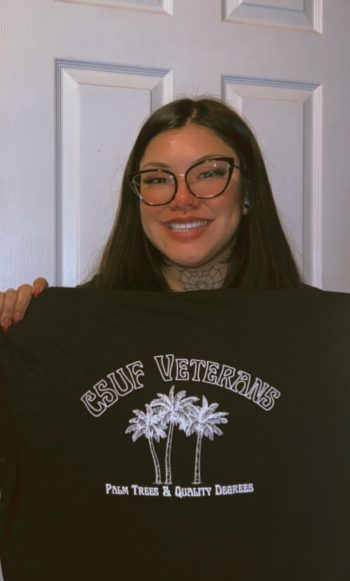 miling figure holding up a t-shirt reading "CSUF Veterans"